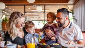 Une famille est assise à une table dans un restaurant, et une variété de plats et de boissons y sont servis.