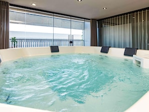 Un jacuzzi con vista a un edificio a través de amplios ventanales.