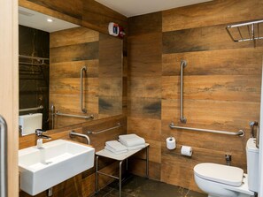 A modern bathroom with wooden paneling, a sink, toilet, and a mirror. - Novotel Criciuma (Criciuma)