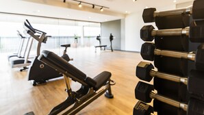 Une salle de sport équipée de matériel d’exercice, notamment des tapis de course et des haltères.
