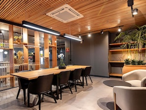 A modern interior with a wooden ceiling, a long table with chairs, and potted plants. - Novotel Criciuma (Criciuma)
