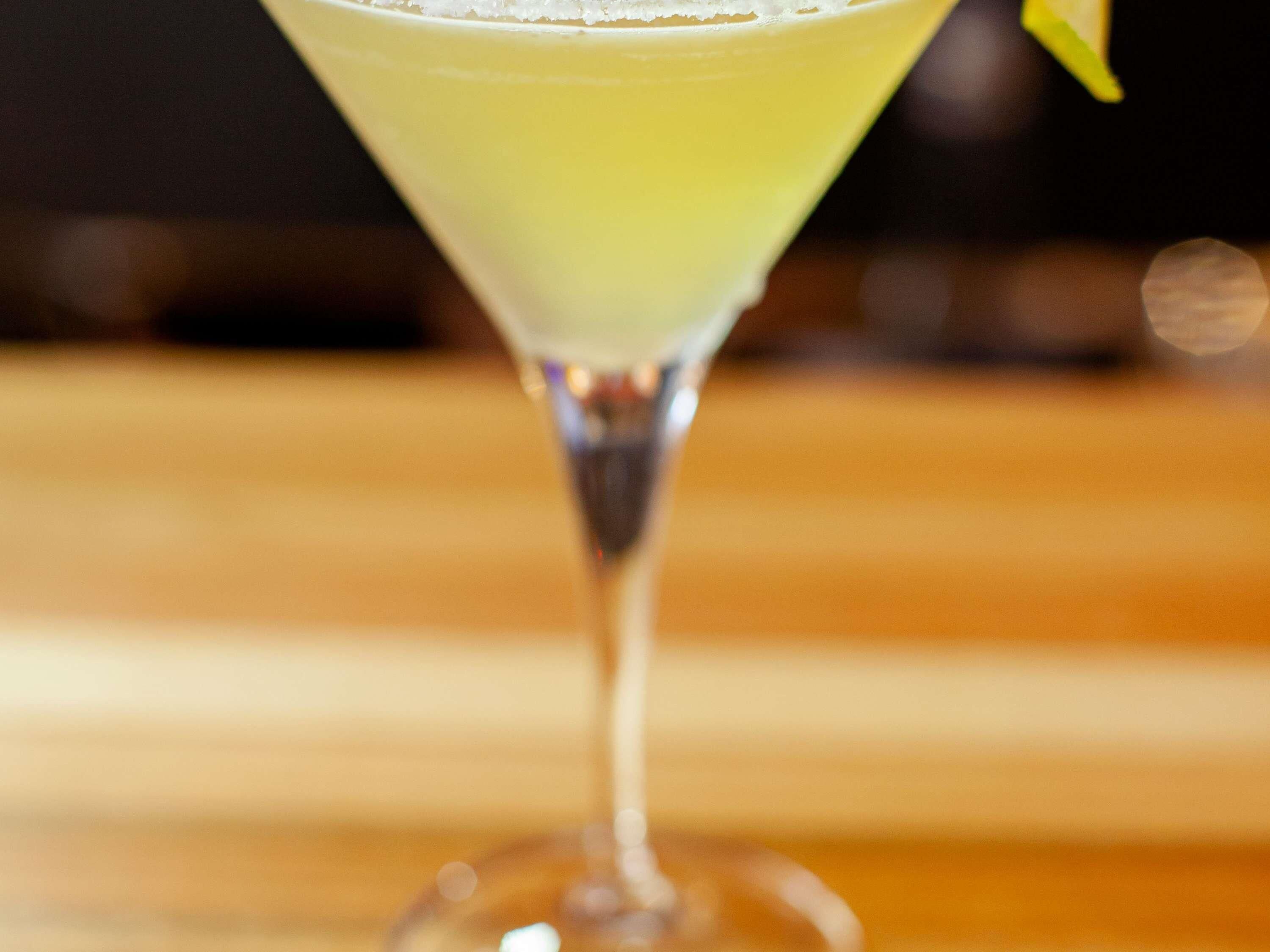 Een cocktail in een martini-glas op een houten ondergrond.