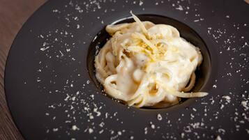 Un plato de pasta con queso rallado sobre un plato oscuro.