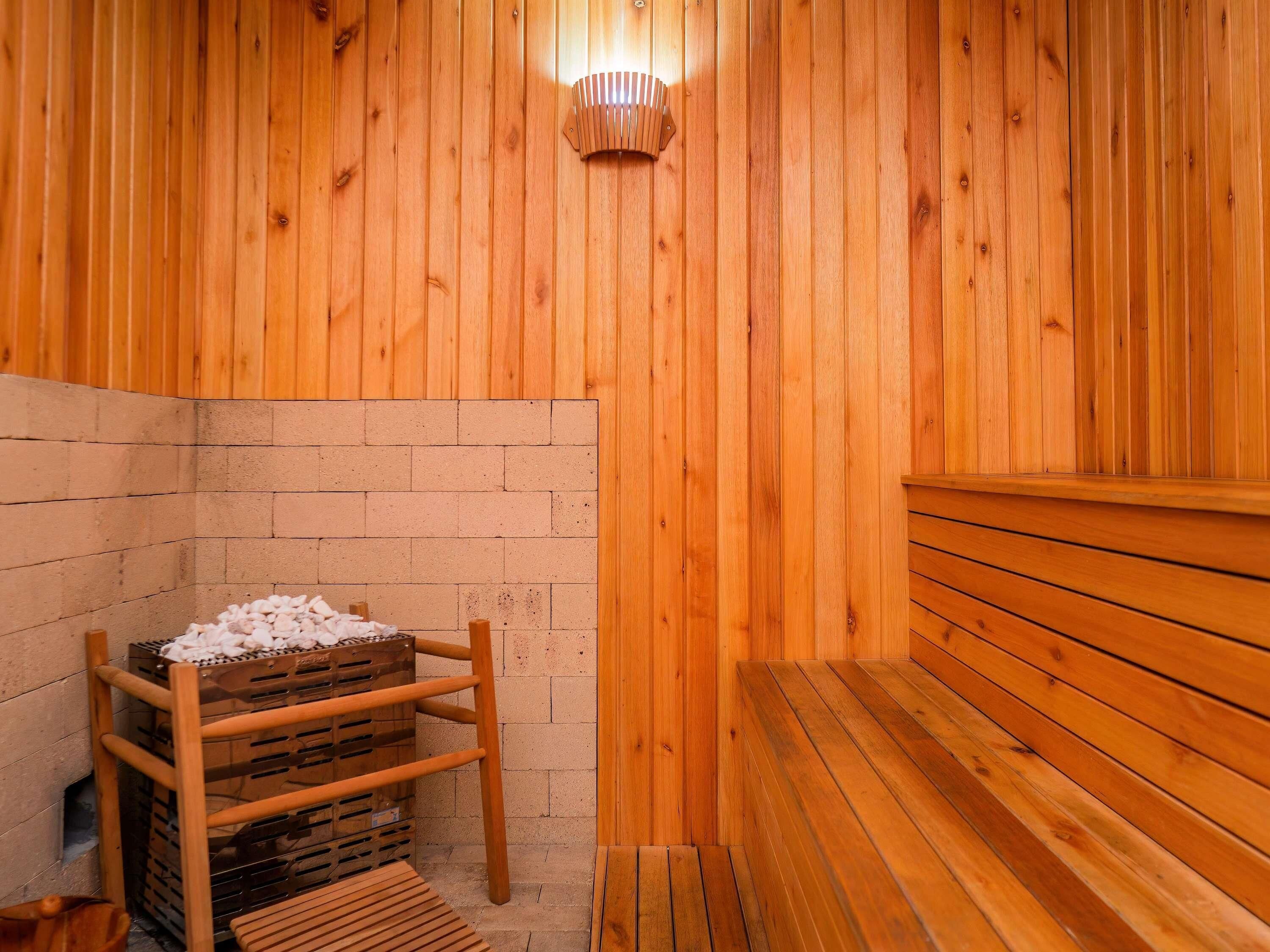 Una sauna con pareti in legno, una panca e una rastrelliera in legno con pietre.