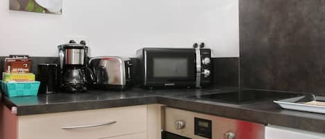 Cocina compacta equipada con microondas, tostadora, cafetera y lavavajillas.