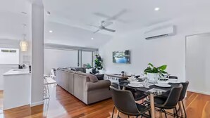 A modern living room with a dining area, a grey sofa, and a ceiling fan.
