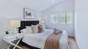 A bedroom with a bed, nightstands, a ceiling fan, a window, and a framed picture on the wall.