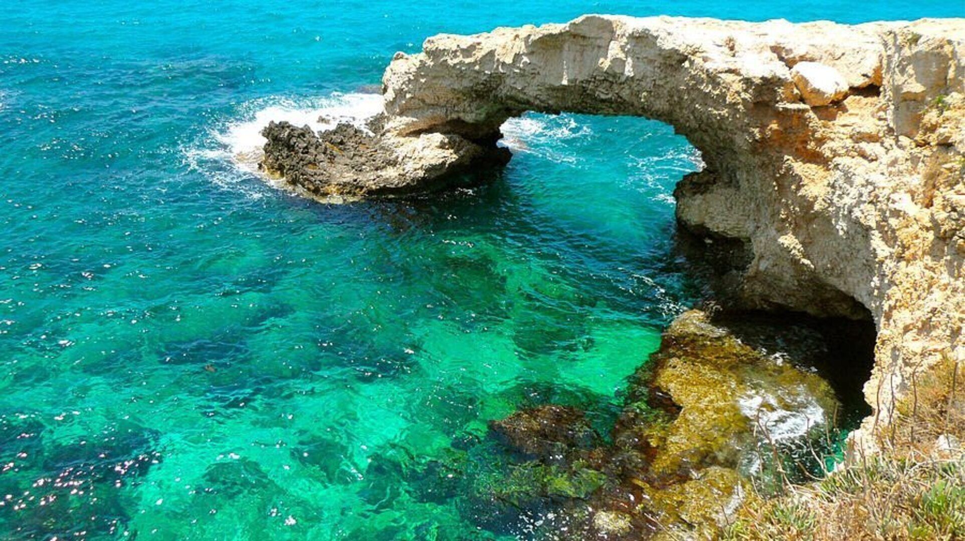 A natural rock formation with a clear blue sea.