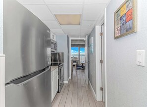 Una cocina con electrodomésticos de acero inoxidable, suelo de madera y vistas a un balcón.