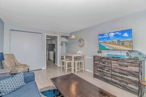 Een woonkamer met een bank, salontafel, televisie en een houten kast met een stadsgezicht op de foto.