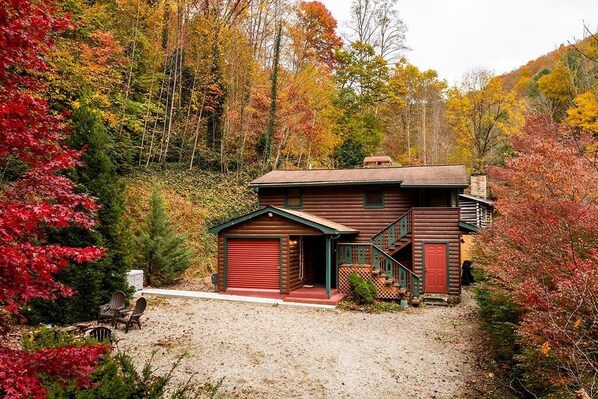 Escape to a cozy cabin nestled in a forest, surrounded by vibrant autumn foliage.