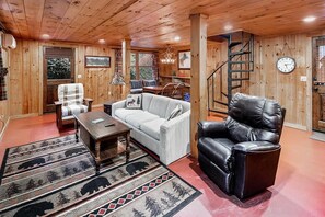 Cozy seating area with sofa, armchair, and table, featuring a patterned rug and framed picture.
