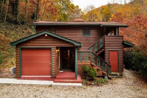 Cozy cabin-style home surrounded by a serene natural landscape with a prominent garage door and a staircase leading to the main entrance.