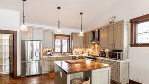 A modern kitchen with wooden cabinets, stainless steel appliances, and pendant lighting. - Luxurious Ski-in Ski-out Home in Arrowhead community (Edwards)