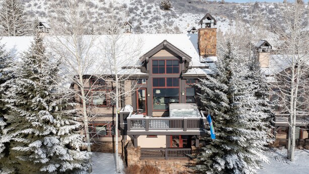 A large lodge with a stone facade, multiple windows, and a balcony with outdoor seating. - Luxurious Ski-in Ski-out Home in Arrowhead community (Edwards)