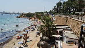 Une plage avec une promenade en bois, des parasols et des chaises de plage.