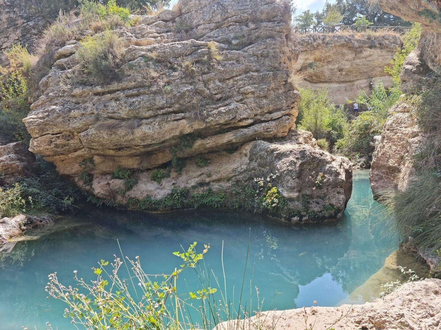 Formación rocosa natural con un cuerpo de agua cristalina al frente.