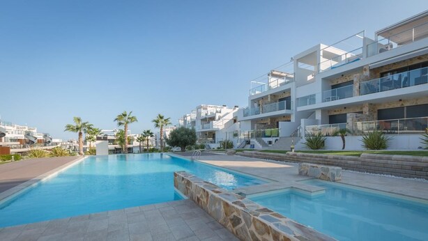 Un complexe résidentiel moderne doté d’une piscine, d’une terrasse en pierre et de nombreux balcons.