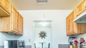 Une cuisine dotée de meubles en bois, d’un four à micro-ondes, d’une cuisinière et d’un coin repas avec une table et des chaises.