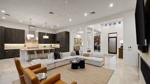 A modern living room with a large L-shaped sofa, a coffee table, and a dining area with bar stools. - Sleek Paradise Valley Escape with Resort Pool and Indoor Outdoor Flow (Paradise Valley)