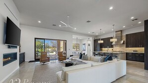 A modern living room with a fireplace, a large sofa, and a dining area with chairs. - Sleek Paradise Valley Escape with Resort Pool and Indoor Outdoor Flow (Paradise Valley)