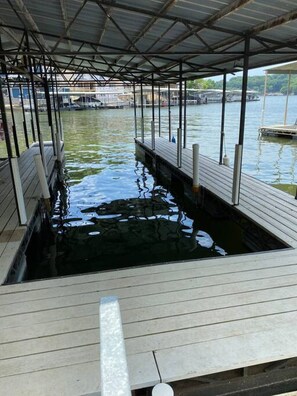 A covered dock area with a wooden walkway leading to a body of water. - Waterfront Cottage & Dock w/ Beautiful View - 5MM (Rocky Mount)