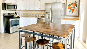 A modern kitchen with white cabinets, a stainless steel refrigerator, a microwave, an oven, and a wooden island with stools. - Waterfront Cottage & Dock w/ Beautiful View - 5MM (Rocky Mount)