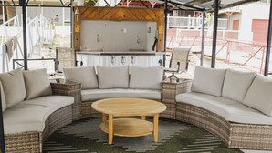 A covered outdoor seating area with a curved sofa, a round table, and a grill. - Waterfront Cottage & Dock w/ Beautiful View - 5MM (Rocky Mount)