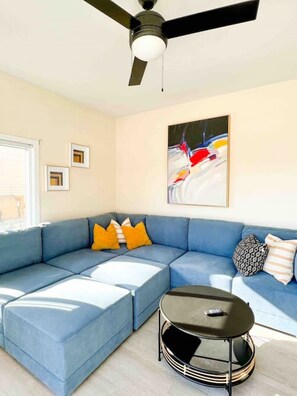 A modern living room with a sectional sofa, a round coffee table, and a ceiling fan. - Waterfront Cottage & Dock w/ Beautiful View - 5MM (Rocky Mount)