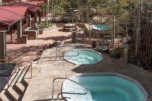 A spa area with two hot tubs, outdoor seating, and a pool.