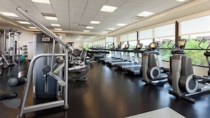 Ein Fitnessstudio mit Laufbändern, Kraftgeräten und einem großen Fenster, das natürliches Licht hereinlässt.