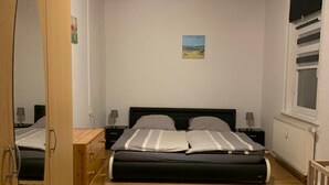 A bedroom with a bed, wooden wardrobe, bedside tables, a window, and a painting on the wall. - Apartment "Squirrel" in the middle of the Thuringian Forest (Suhl)