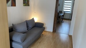 A modern living room with a grey sofa, a wooden floor, and a painting on the wall. - Apartment "Squirrel" in the middle of the Thuringian Forest (Suhl)