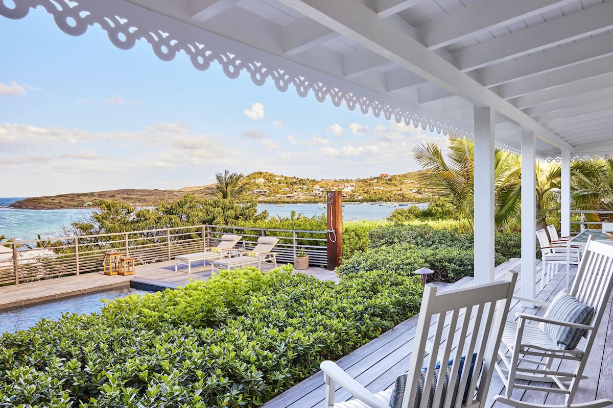 A covered outdoor area with a pool, lounge chairs, and a view of the sea.