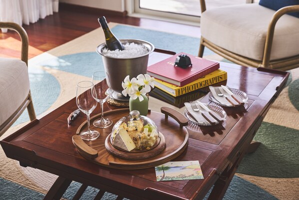 A wooden tray with a bottle of champagne, glasses, a cheese platter, and a small book on a table.