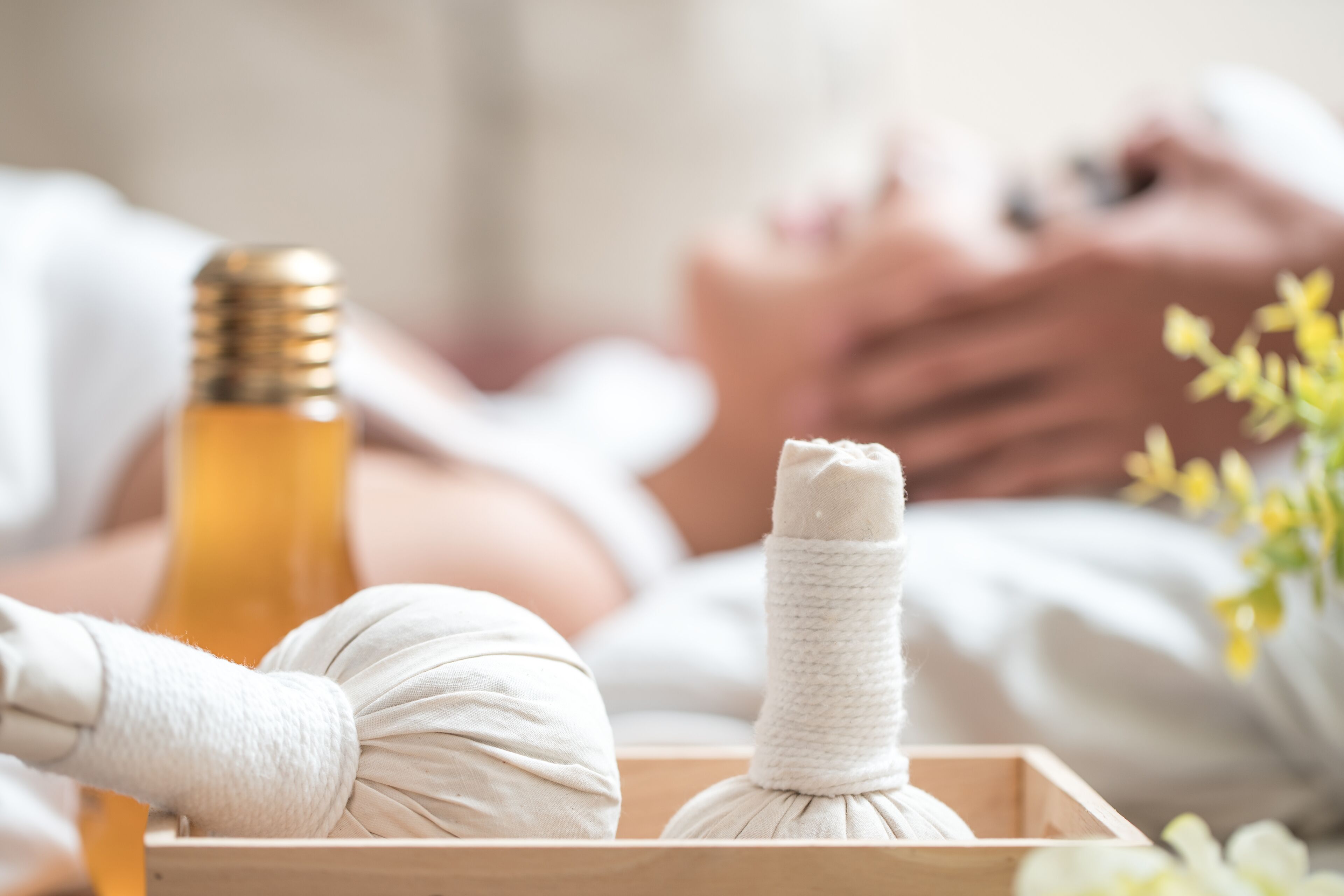 A wooden tray with two white massage balls and a bottle of oil.