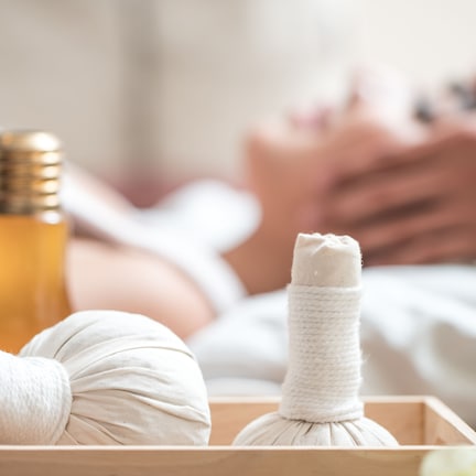 A wooden tray with two white massage balls and a bottle of oil.
