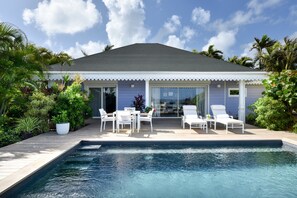 A modern house with a swimming pool, white outdoor furniture, and lush greenery. - Rosewood Le Guanahani St Barth (St. Barthelemy)