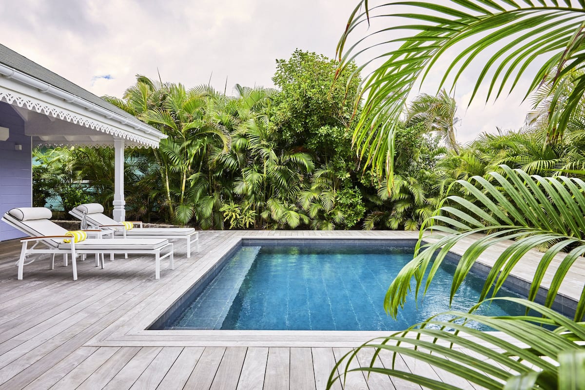A rectangular swimming pool with a wooden deck and lounge chairs.