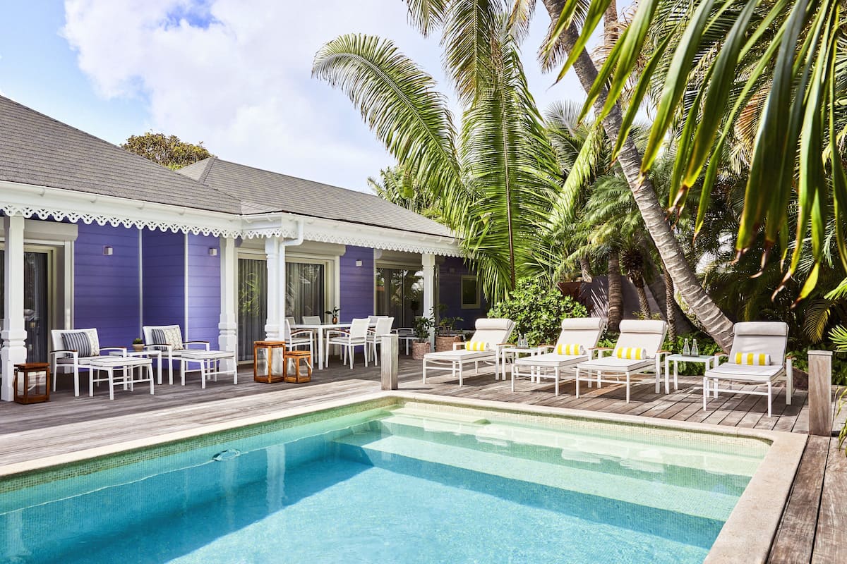 A poolside area with white lounge chairs and a wooden deck.
