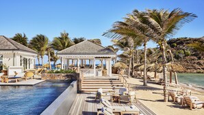 A resort with a pool, lounge chairs, and a gazebo. - Rosewood Le Guanahani St Barth (St. Barthelemy)