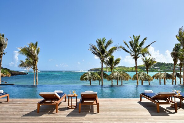 A wooden deck with lounge chairs and a pool overlooking the ocean. - Rosewood Le Guanahani St Barth (St. Barthelemy)