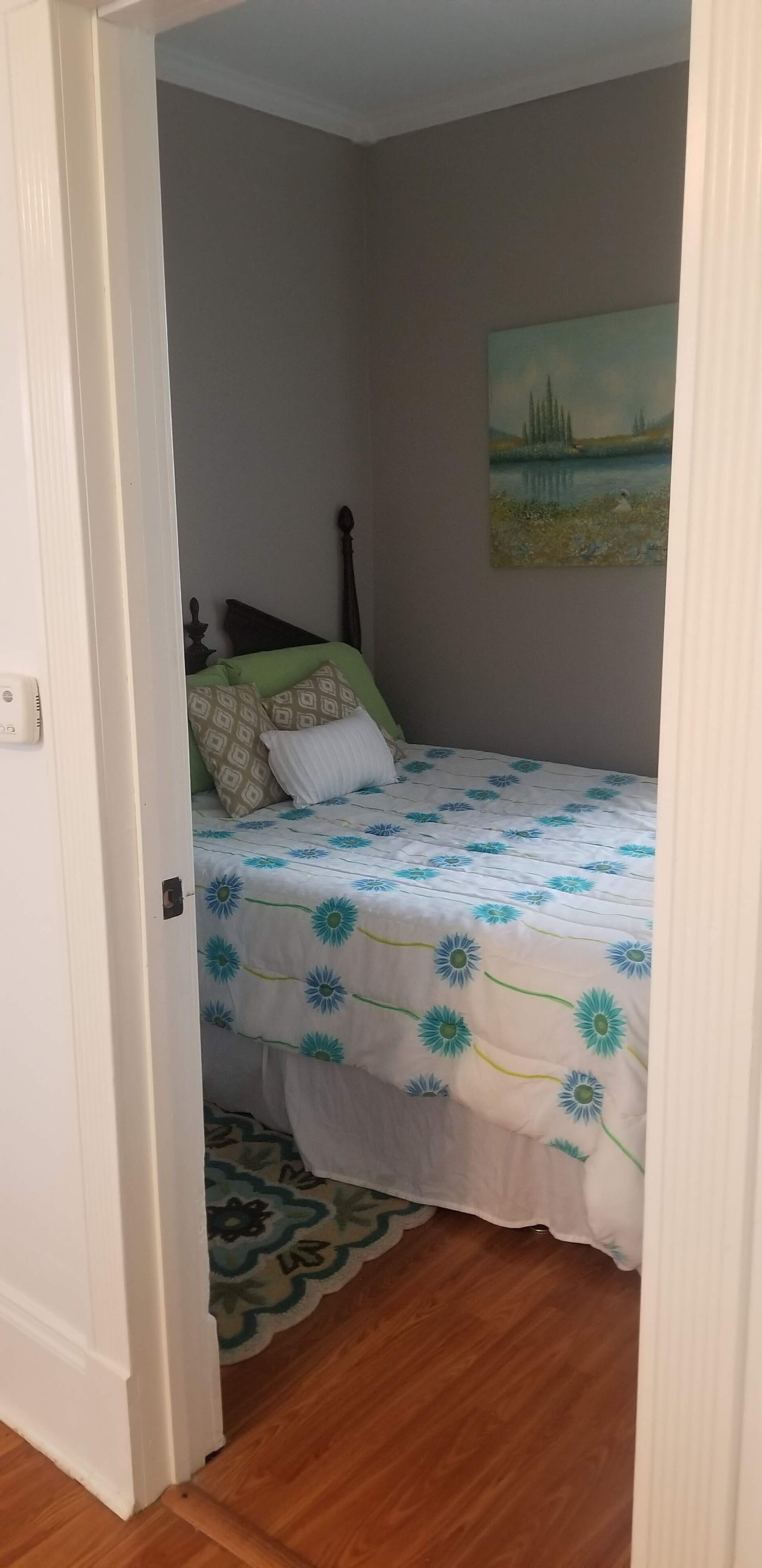 Une chambre à coucher avec un lit, un tableau et un plancher en bois.
