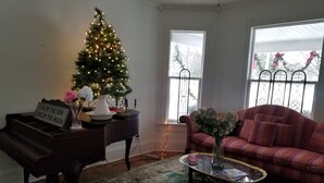 A living room with a piano, a Christmas tree, a couch, and a coffee table.