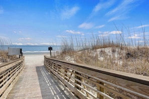 A wooden boardwalk leading to a beach with a clear sky.