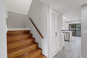 A staircase with wooden steps and a wooden handrail leading to a white door.