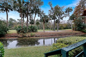 A tranquil outdoor area with a pond, surrounded by various trees and a grassy field.