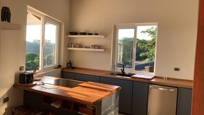 A modern kitchen with wooden countertops, a built-in dishwasher, and two windows offering views of greenery. - House with terrace and pool. (Playa Negra Finca Los Pargos)