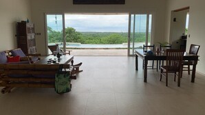 A spacious living area with a large sliding glass door leading to a balcony with a view of lush greenery and a body of water. - House with terrace and pool. (Playa Negra Finca Los Pargos)