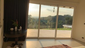 A room with a large sliding glass door leading to an outdoor area, a small table with decorative items, and a bed with a patterned bedspread. - House with terrace and pool. (Playa Negra Finca Los Pargos)